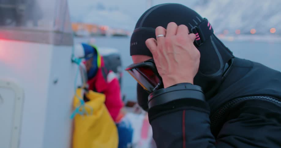 A person in a wet suit puts goggles on