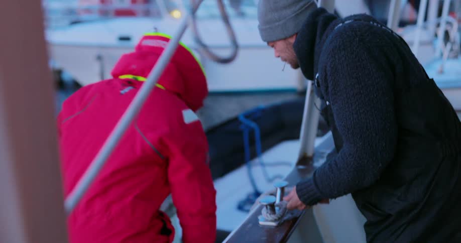 A man tethers a small boat to a larger boat