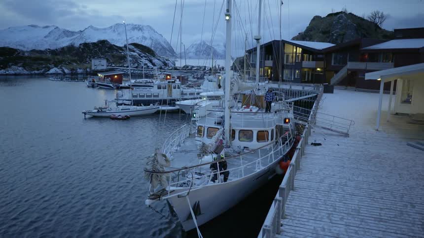 A man is untying a rope on a ship at dusk