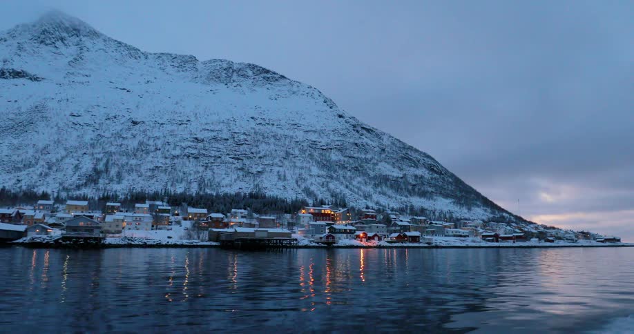 A boat floats off a snowy coast at sunset