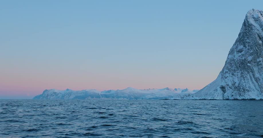 Water flows in front of snowy mountains at sunrise