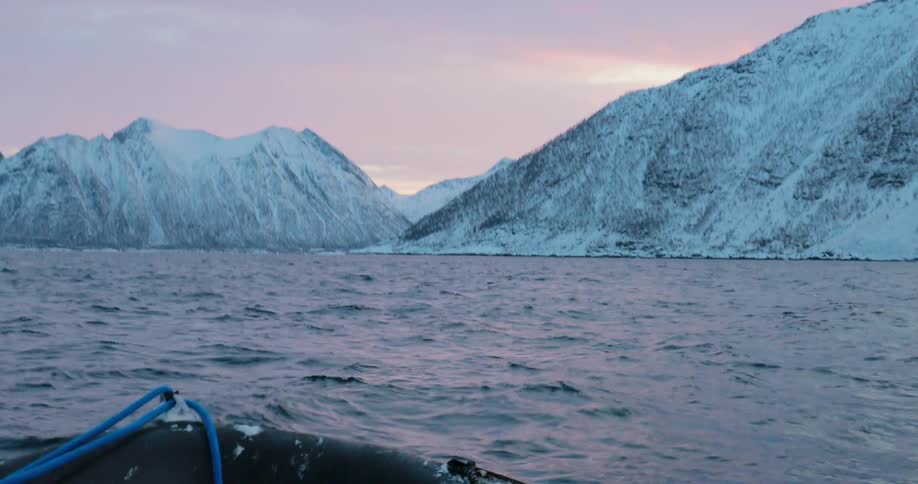 A raft floats off a snowy coast at sunset