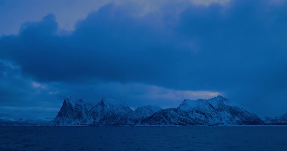 Clouds float over snowy coastal mountains