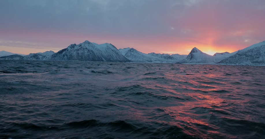 The ocean tide is rising and falling off a snow-covered coastline at dawn