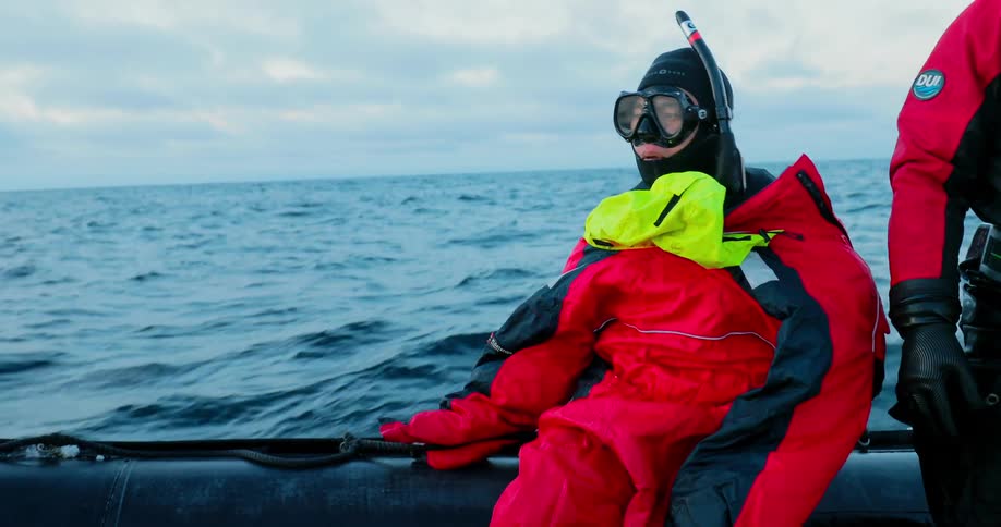 A woman and a man ride on a boat through choppy ocean water with clouds in the sky