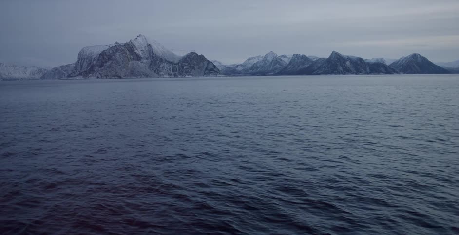 Snowy mountains sit on a shoreline