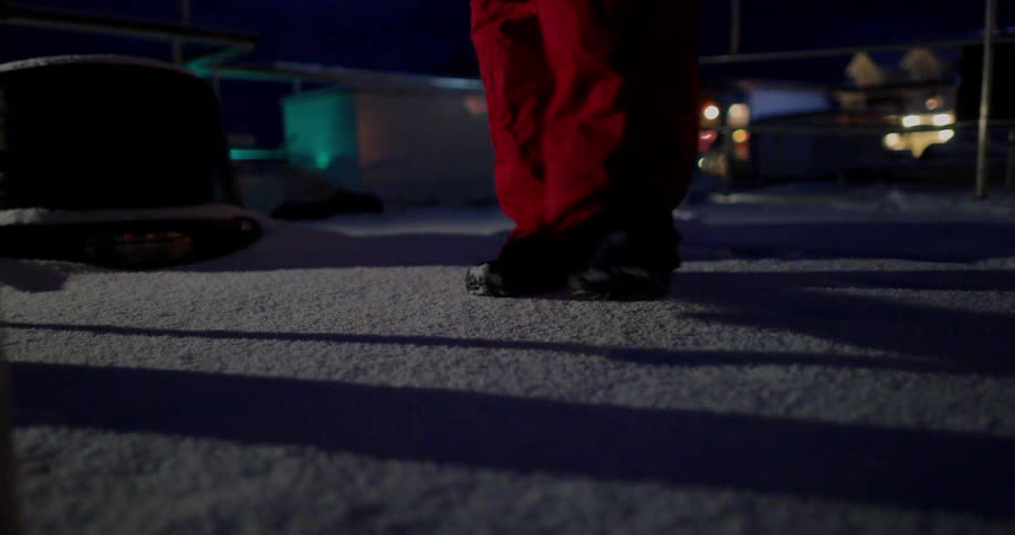 A man walks on a snow covered boat deck at night