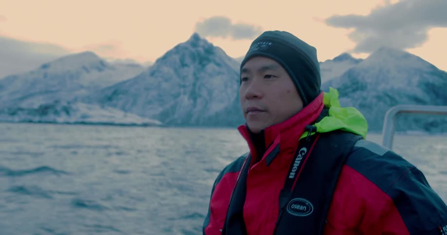 Man riding on a boat in a very cold area with some clouds