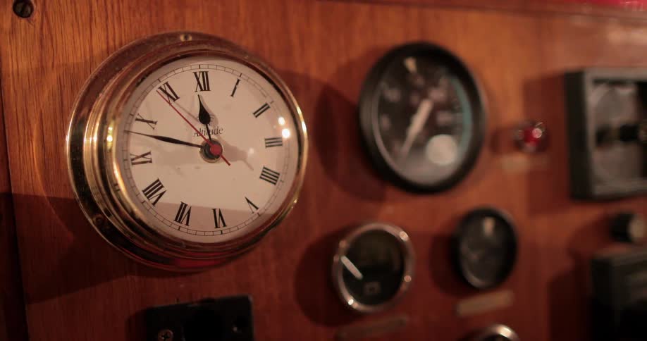 A clock and dials on a wooden dashboard