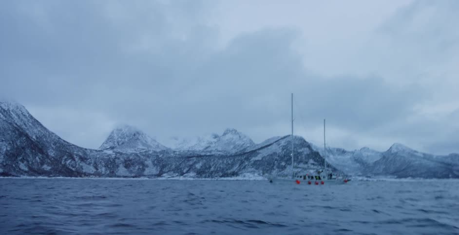 A boat floats just off a snowy shoreline