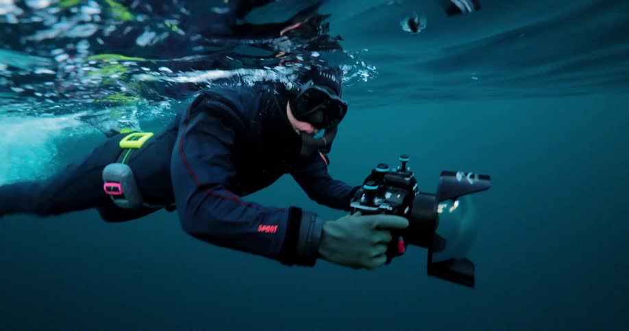 Diver swimming near the surface of the water filming sea life