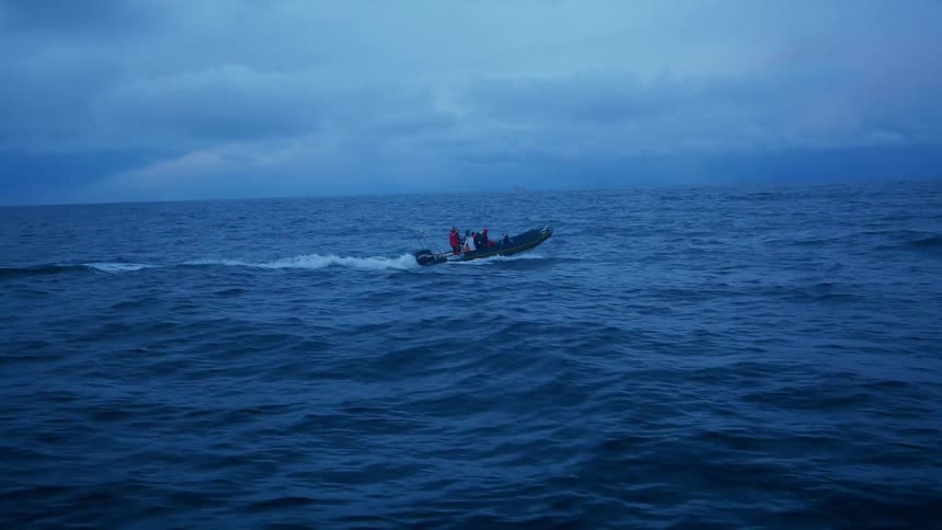 Small boat moving quickly on a large body of water on a cloudy day