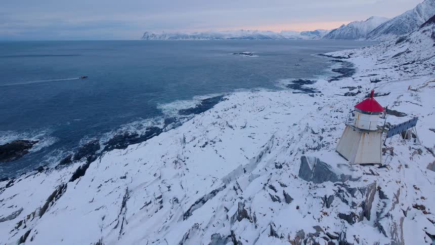 A boat travels on the water by the icy shore