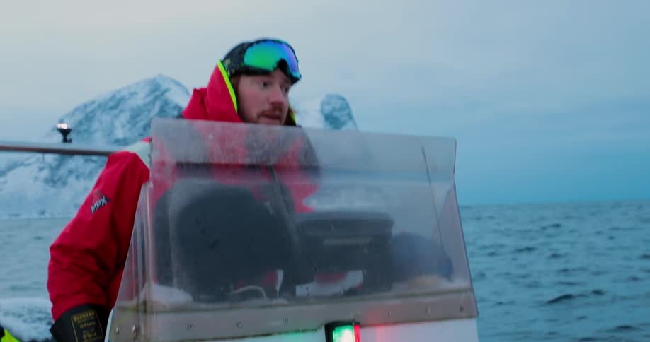 Man wearing goggles rides a small boat in the open water