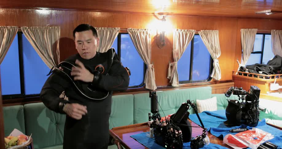 A man wears a wet suit inside a boat cabin