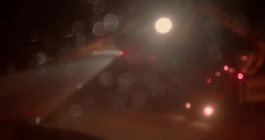 Light shines on a window with water drops on it