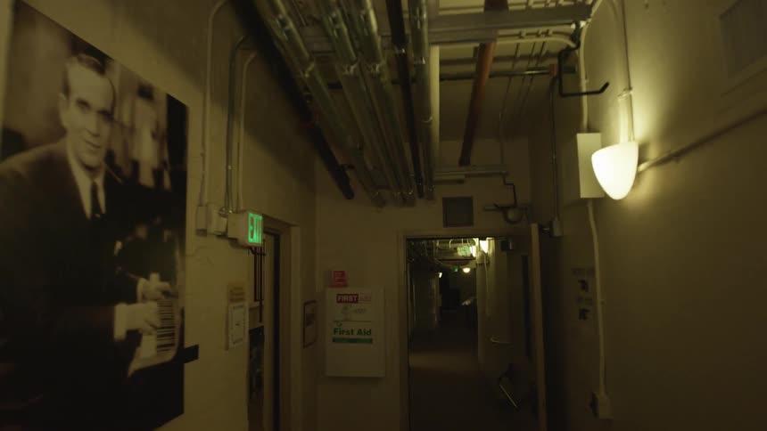 Pictures line the walls of a dim hallway