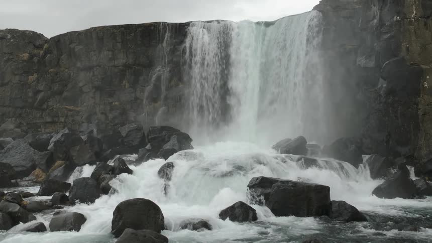 Water falls off the cliff into streaming water