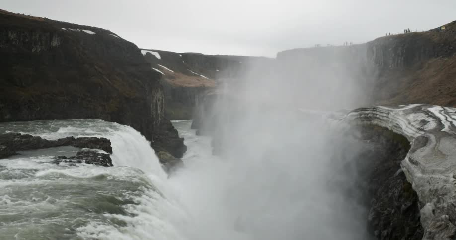 A waterfall is sending up plumes of mist as it plummets into a river