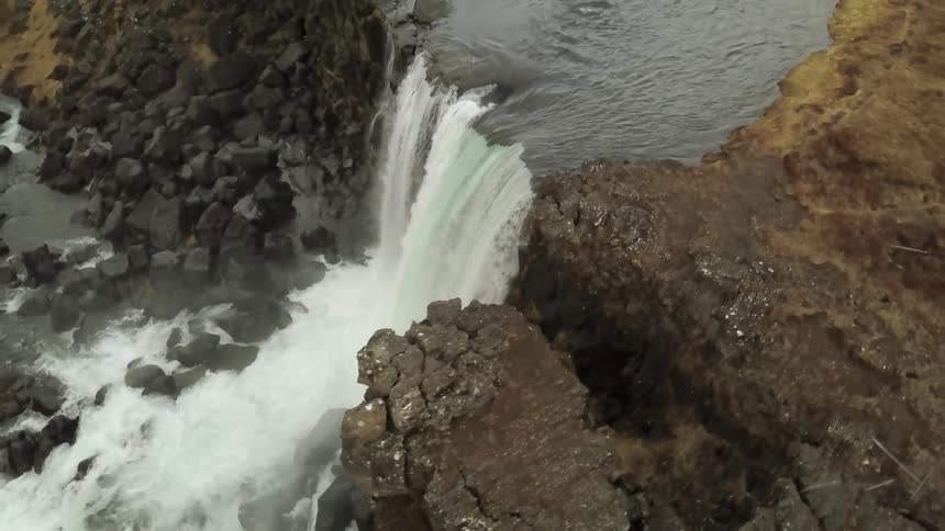 A waterfall flows over a rocky cliff