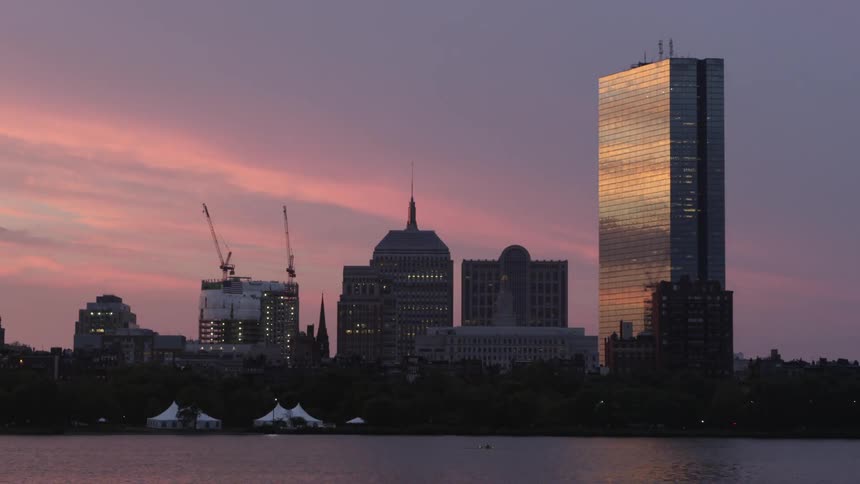 City buildings sit across water at sunset