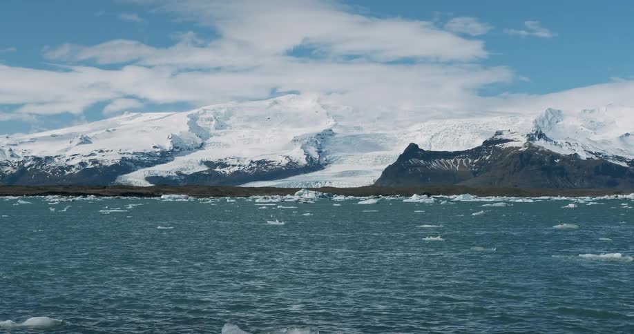 Water flows in front of snowy mountains