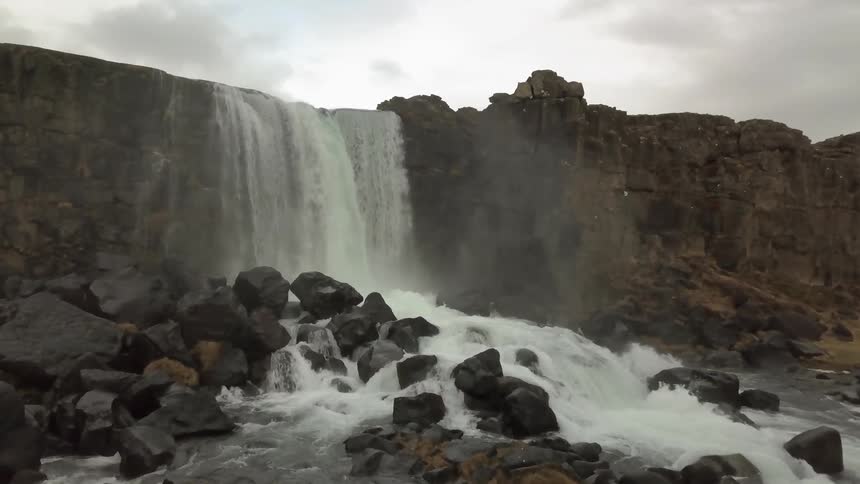 Water falls off a small cliff down into a stream
