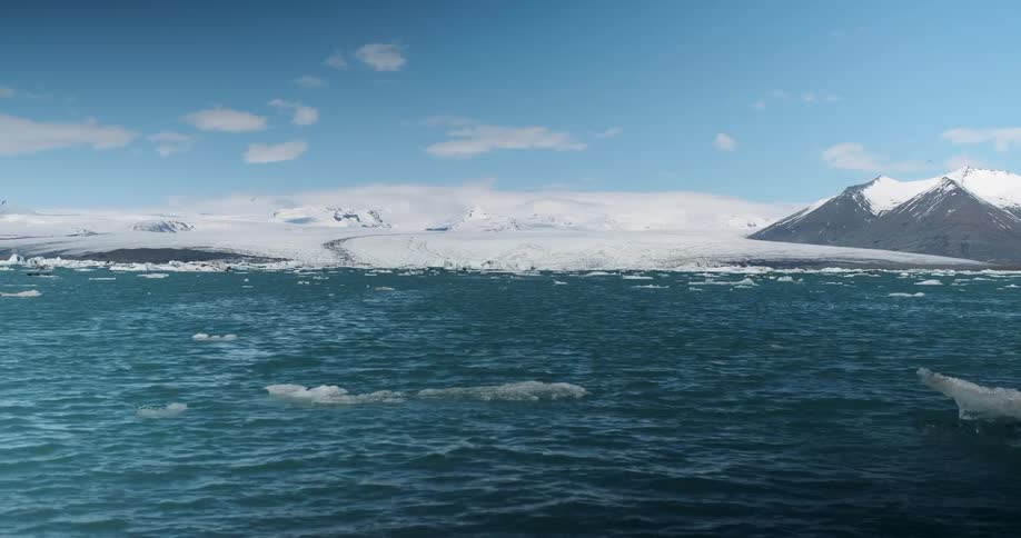 Ocean water ripples next to a snowy shoreline