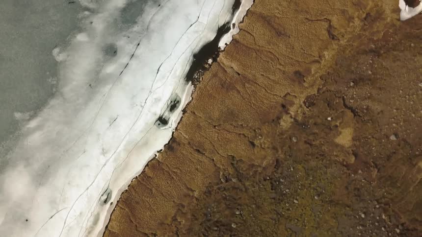 Ice covers the water as it meets the shore