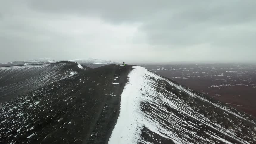 People walk atop a large snow covered mountain