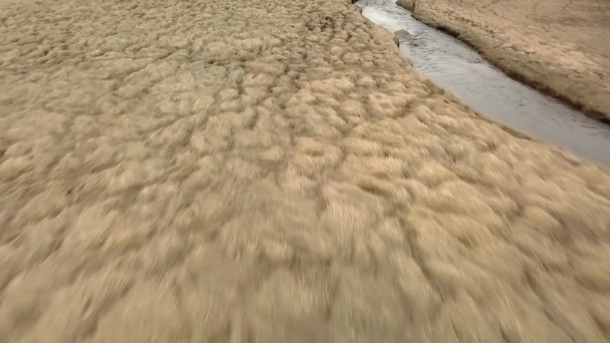 A river is flowing through the tundra on a steppe during the day