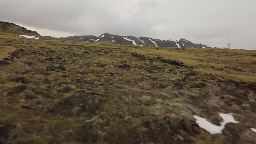 Snow and ice sparsely cover the hilly landscape