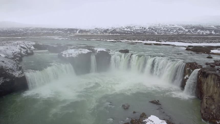 Water flows down the cliff into a pooling lake