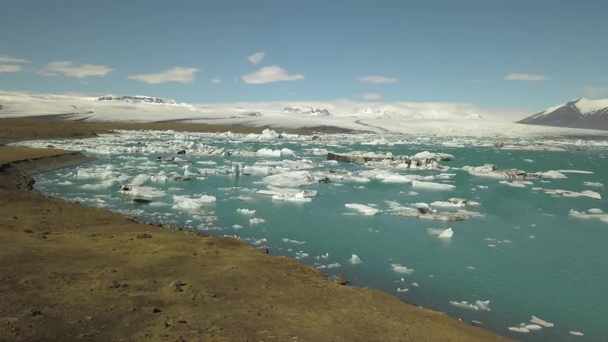 Icebergs are floating in the ocean at the edge of a glacier during the day