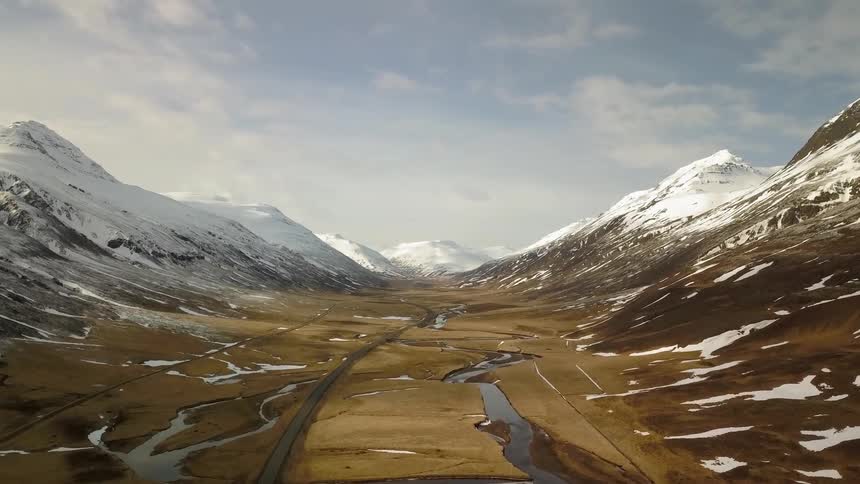 Beautiful river flows through a valley with white capped mountains