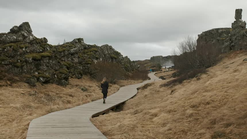 A woman walks on a wood walkway on a cloudy day