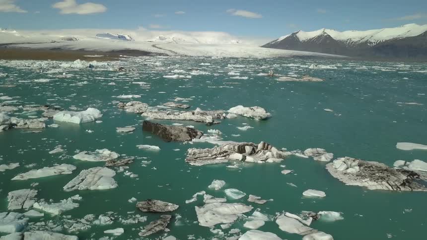 Icebergs are floating in the ocean at the edge of a glacier during the day