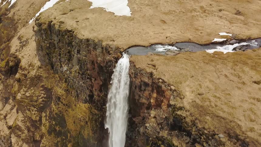 Water falls off the side of a stone mountain