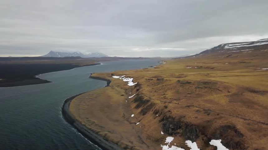Waves come to shore on a barren landscape
