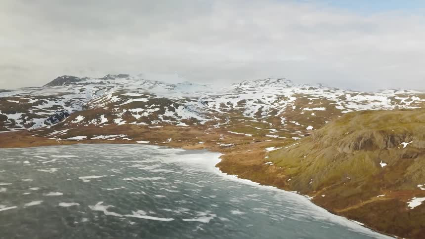 Partially frozen waters sit still by the mountain shore