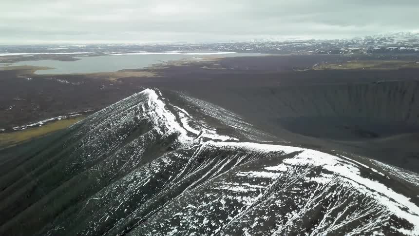 Snow lines the raised ridge of a crater