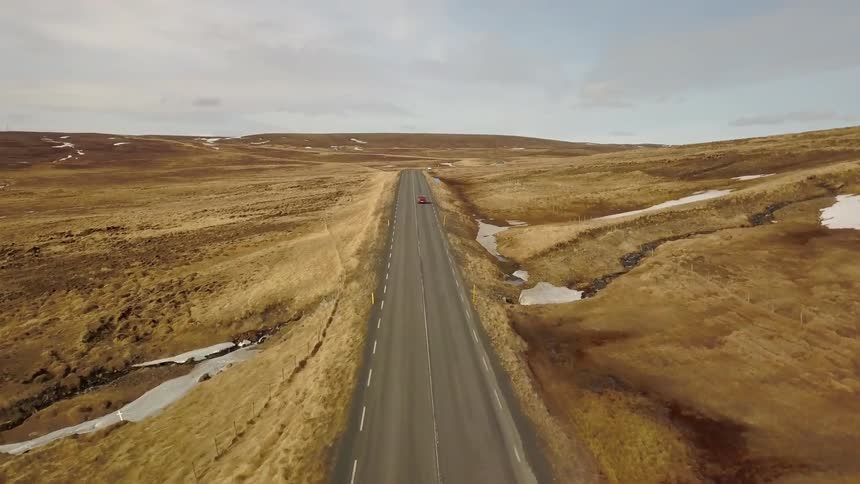 Car travels down a deserted highway in the desert
