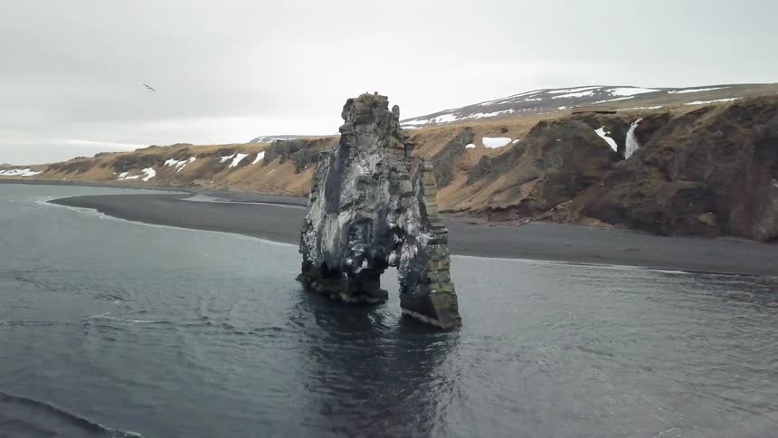A rock formation sits on an ocean coast