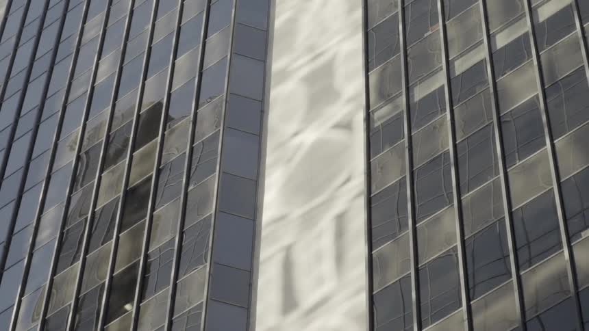 Other office buildings are reflected on the glass of a tall building