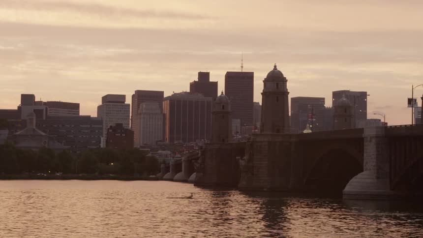 Man rowing down a river in front of a city on a cloudy day