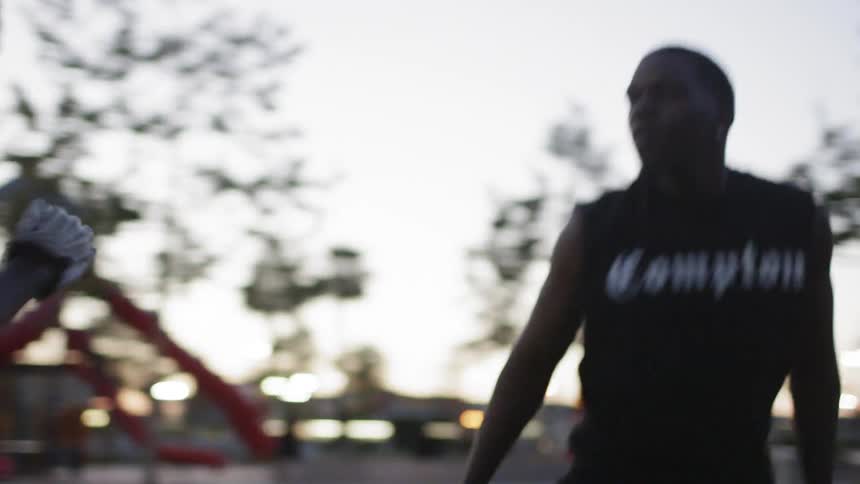 Man leans over and runs in a park at sunset