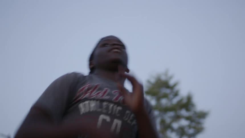 Teenager passing a football outdoors in a city