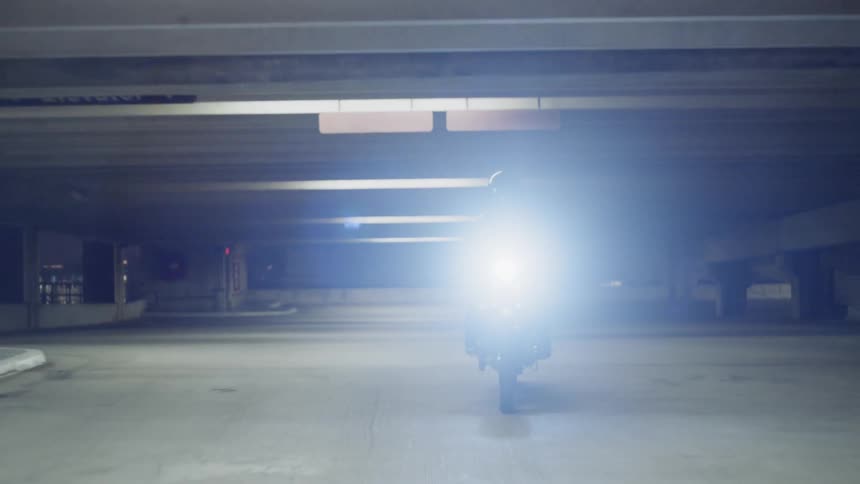 A person is riding a motorcycle in a parking garage at night