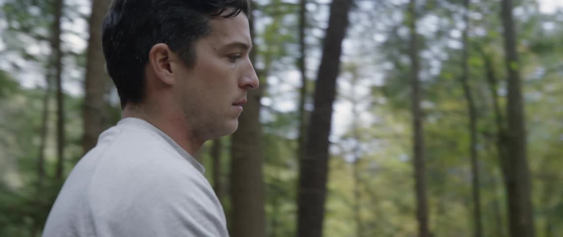 A man sets up a tent in the woods