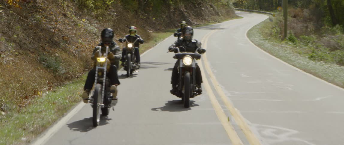 A group of motorcyclists ride on a mountain road